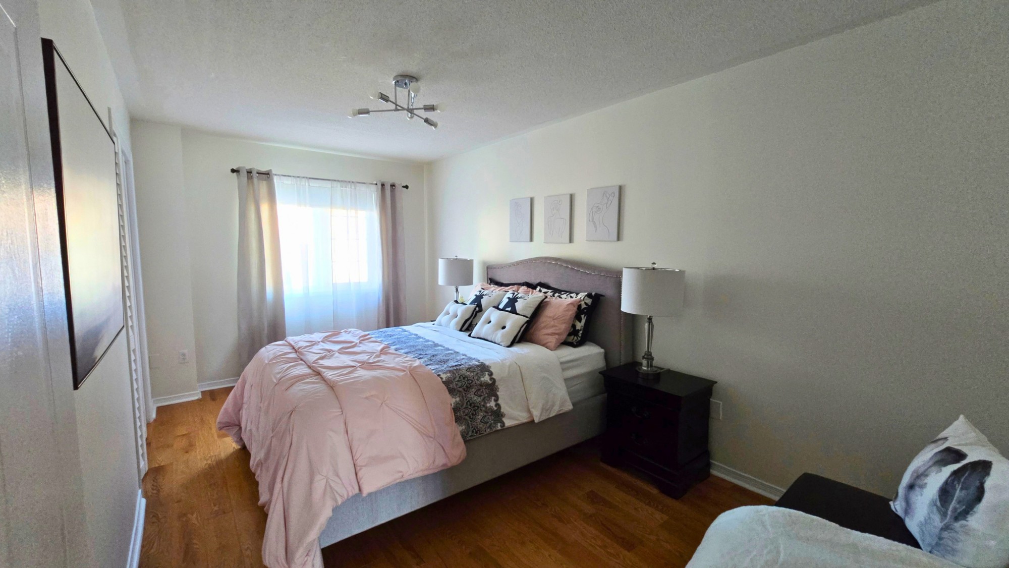 Bedroom with a large bed, hardwood floors and a curtained window