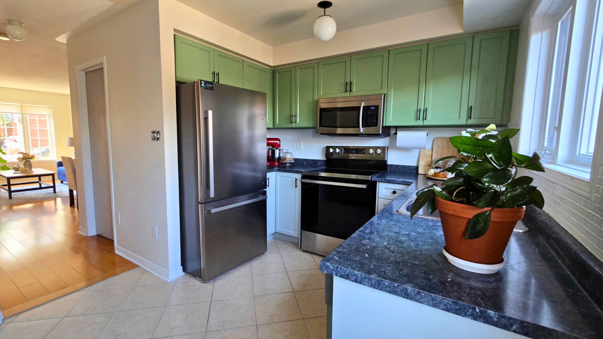 Kitchen with green cabinets, dark countertops, stainless-steel appliances and a window