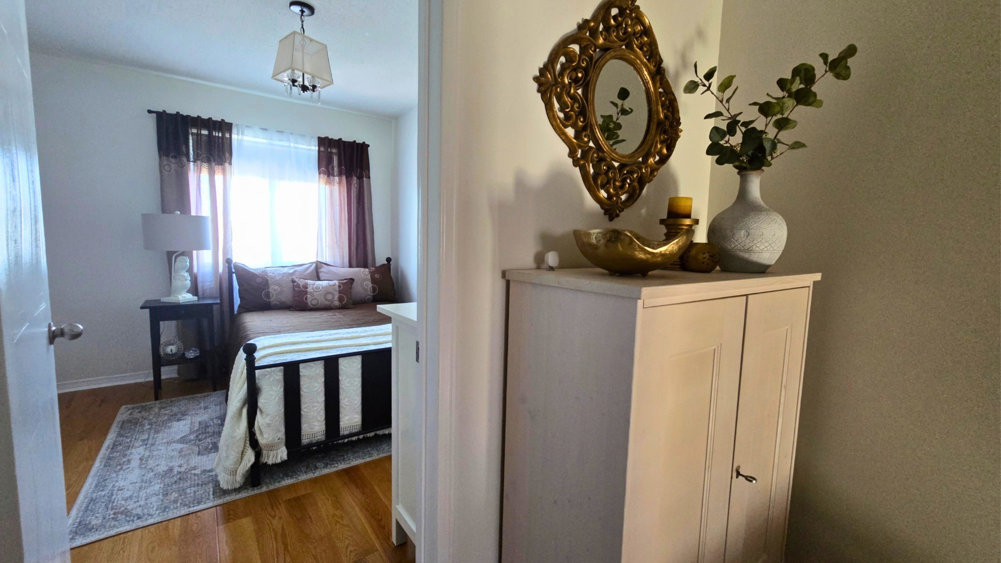 Upstairs landing with a storage cabinet and decorative mirror beside a bedroom doorway