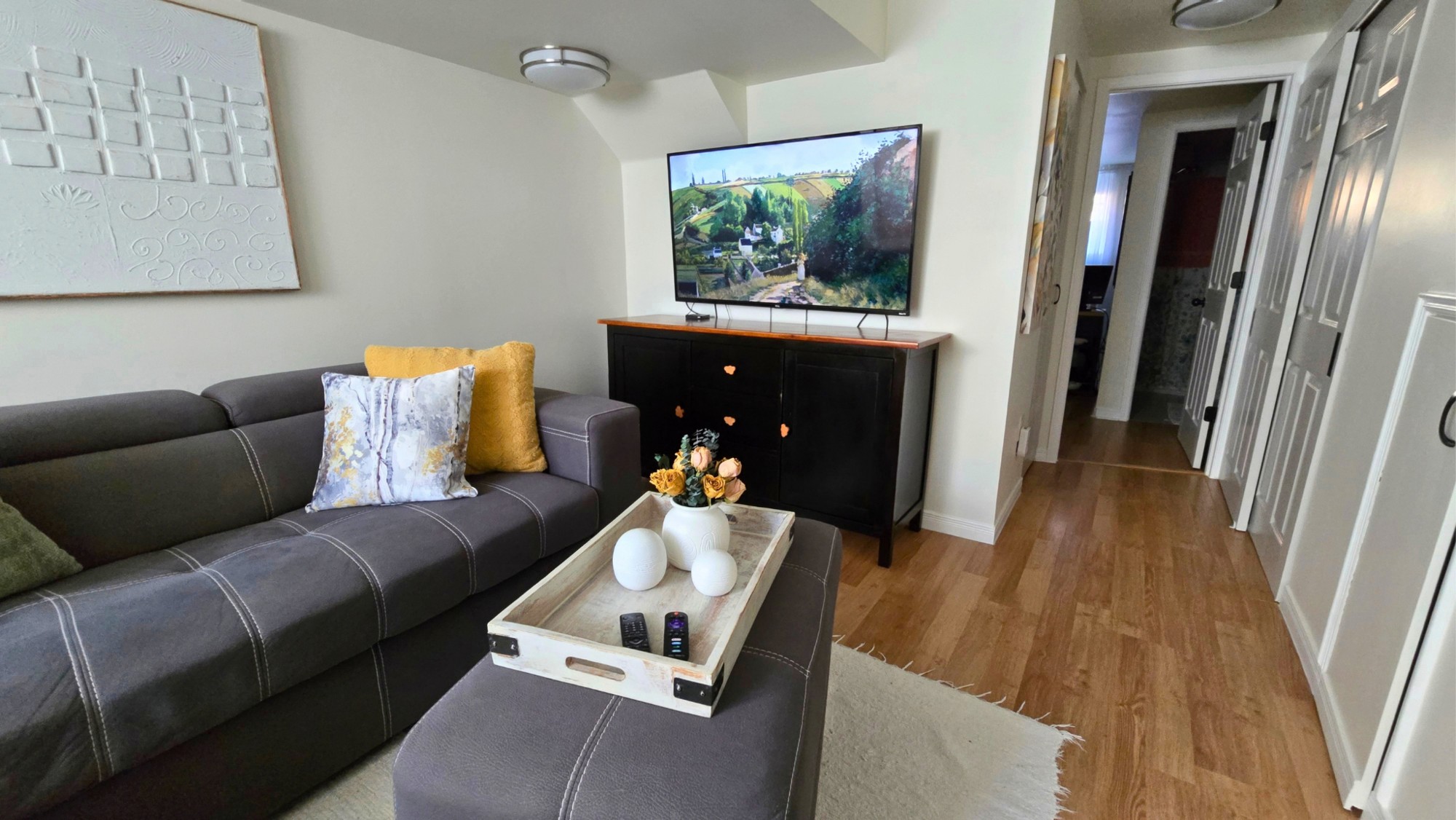 Lower-level recreation room with a grey sectional sofa, coffee table and television